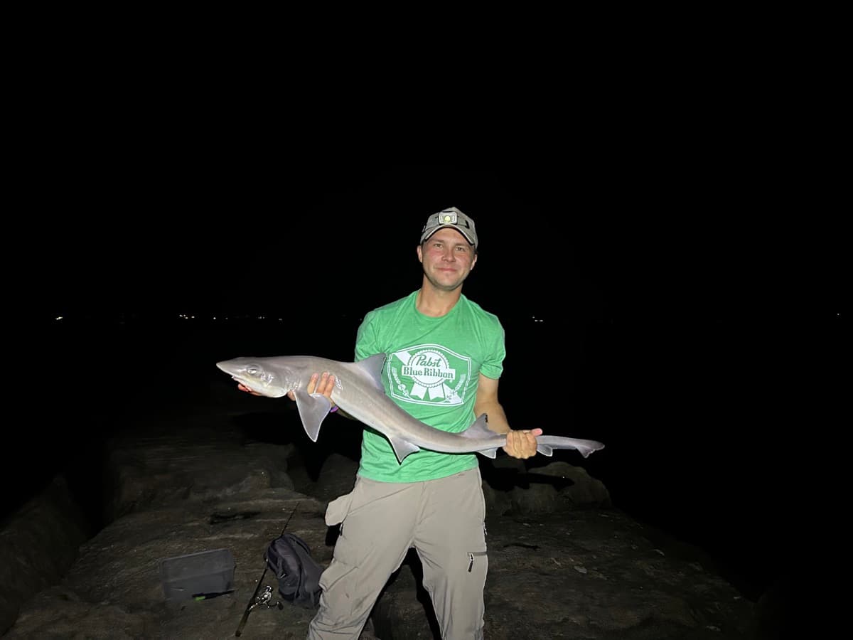 Aidan Perkins holding a shark at night on the Long Island shore